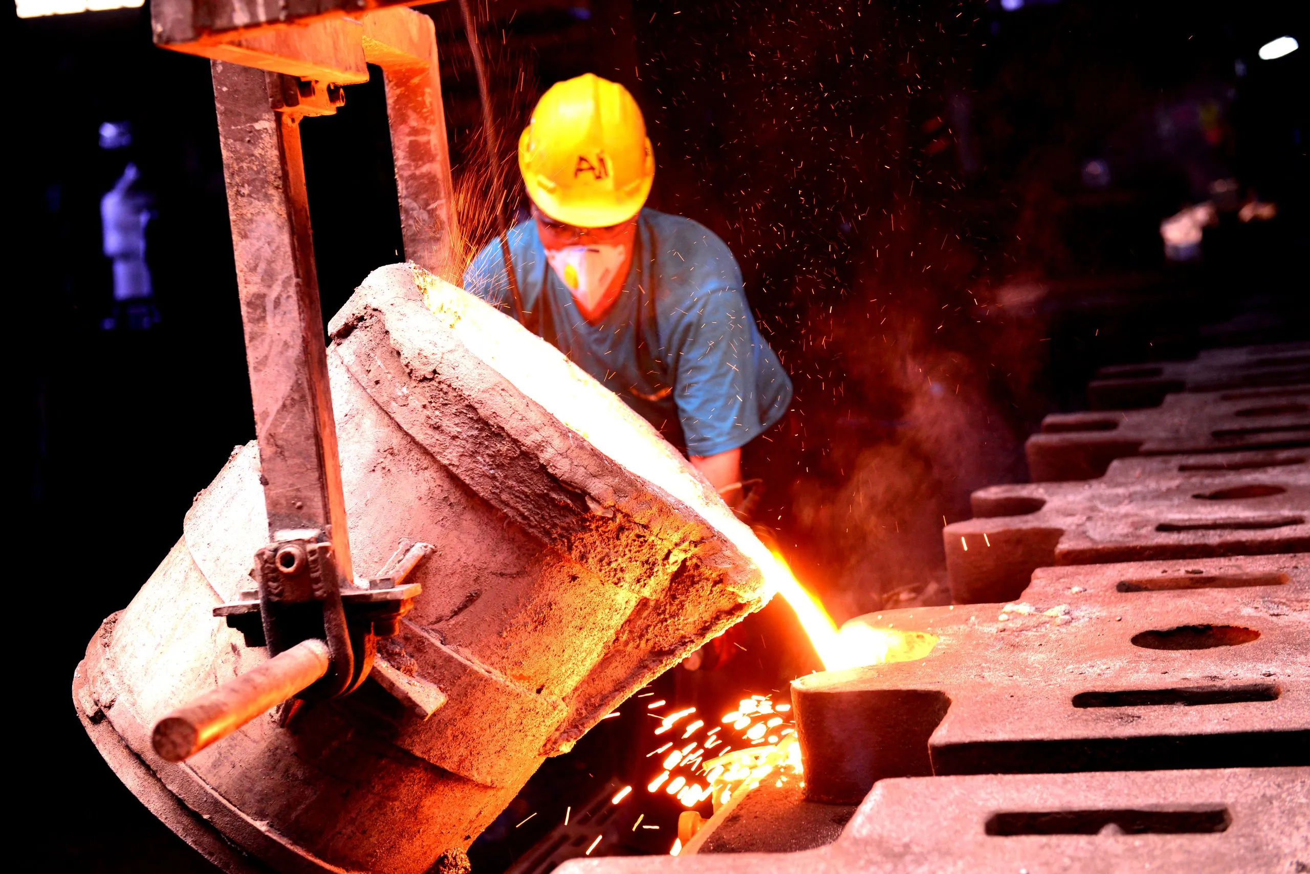 Foundry worker pouring molten metal into moulds