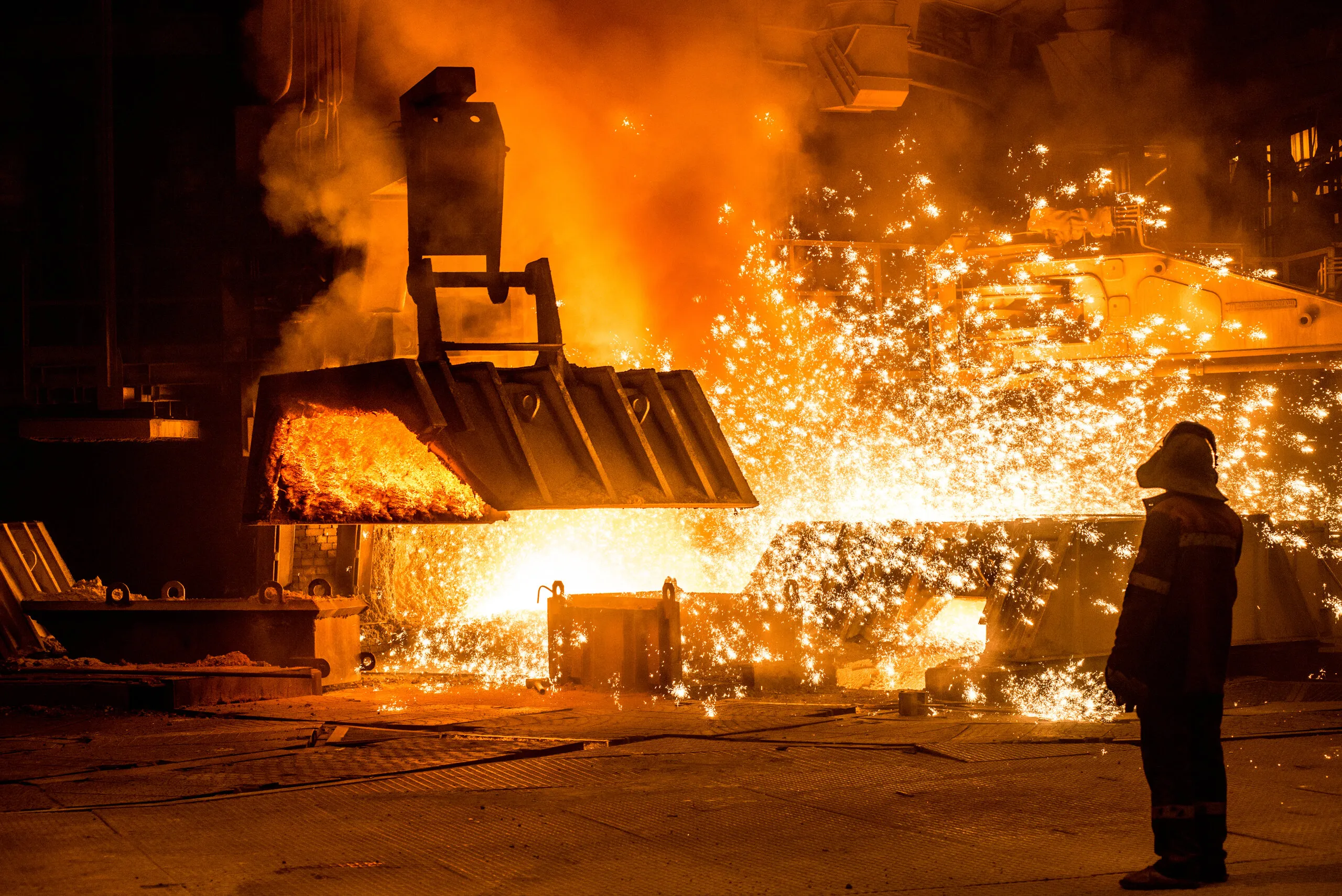 Molten steel being tapped, a worker watching from the side